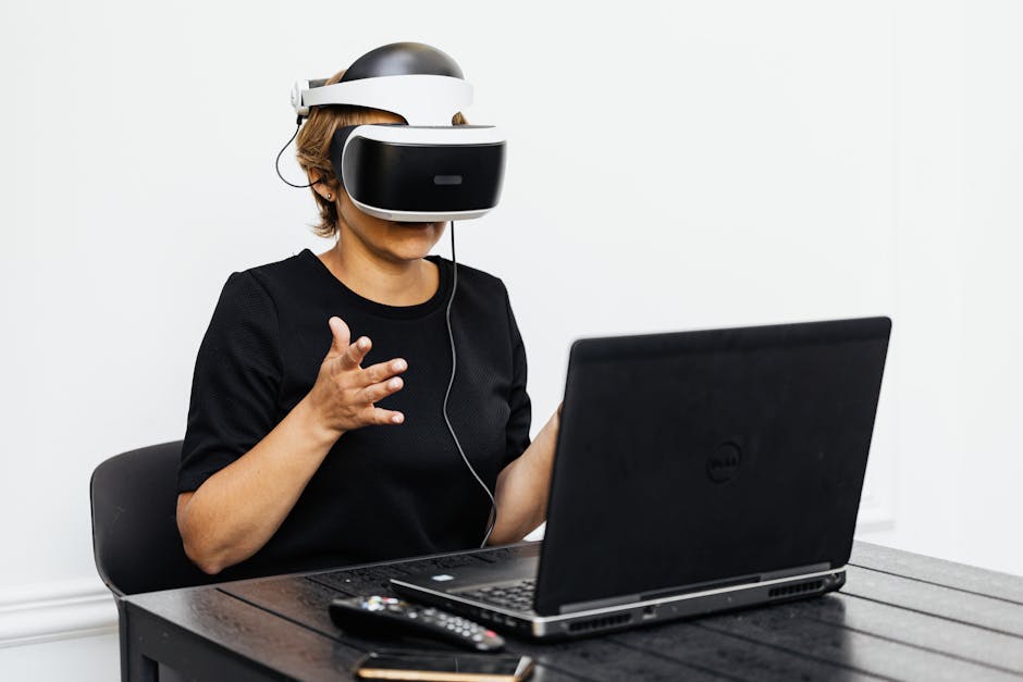 A woman using VR headset while working on a laptop indoors.